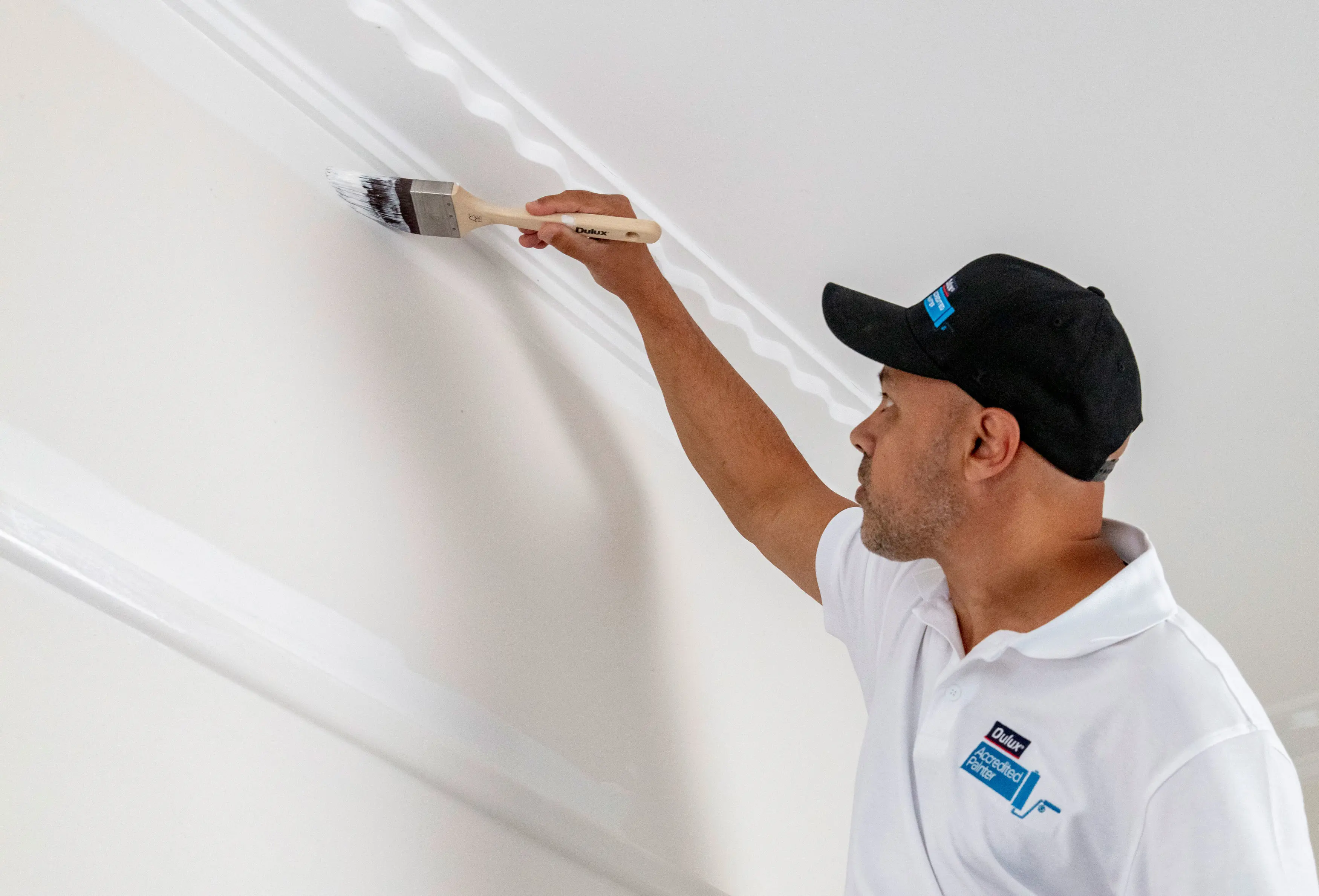 Dulux painter wearing cap painting white wall