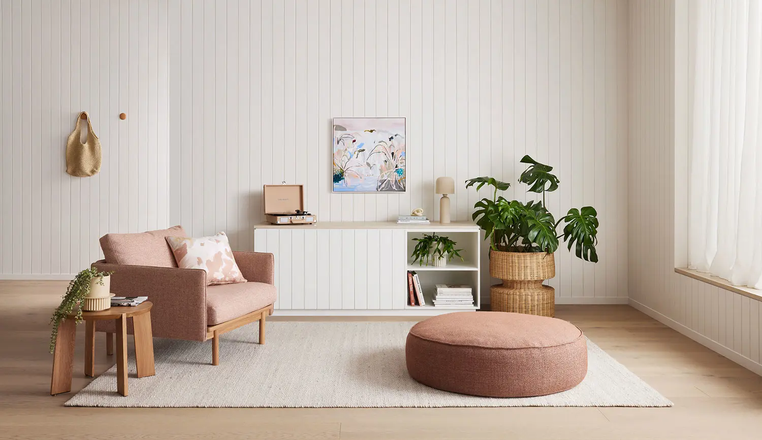 Living room with chair, buffet against wall and plant with artwork featured on wall. 