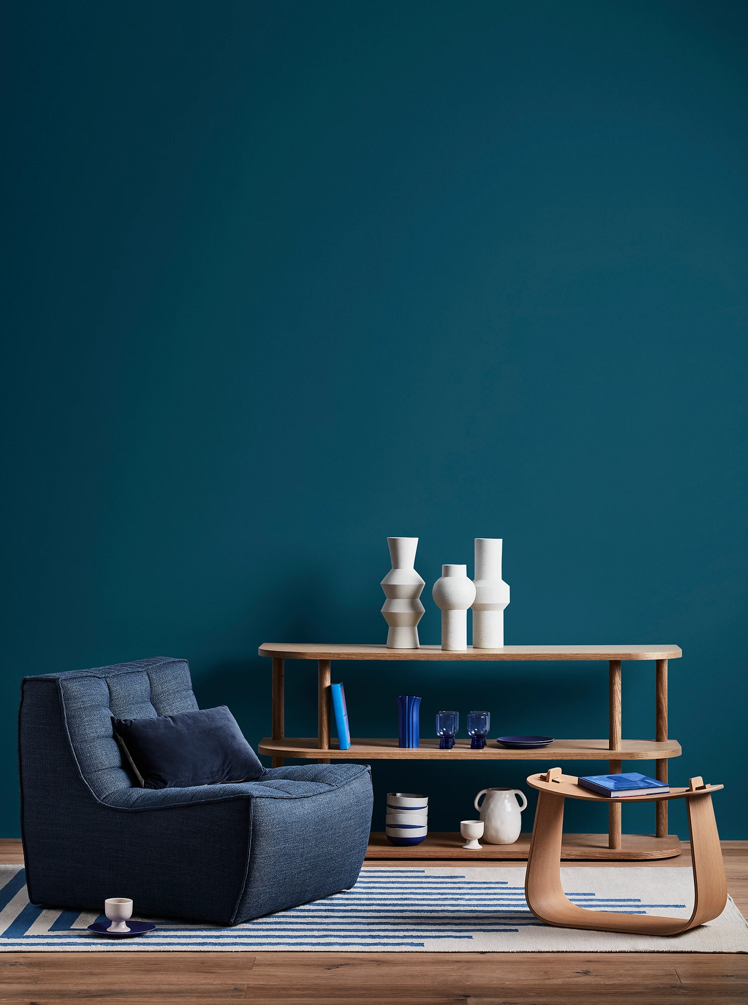 Blue living room with blue armchair, wooden coffee table and shelves with blue and white decor.