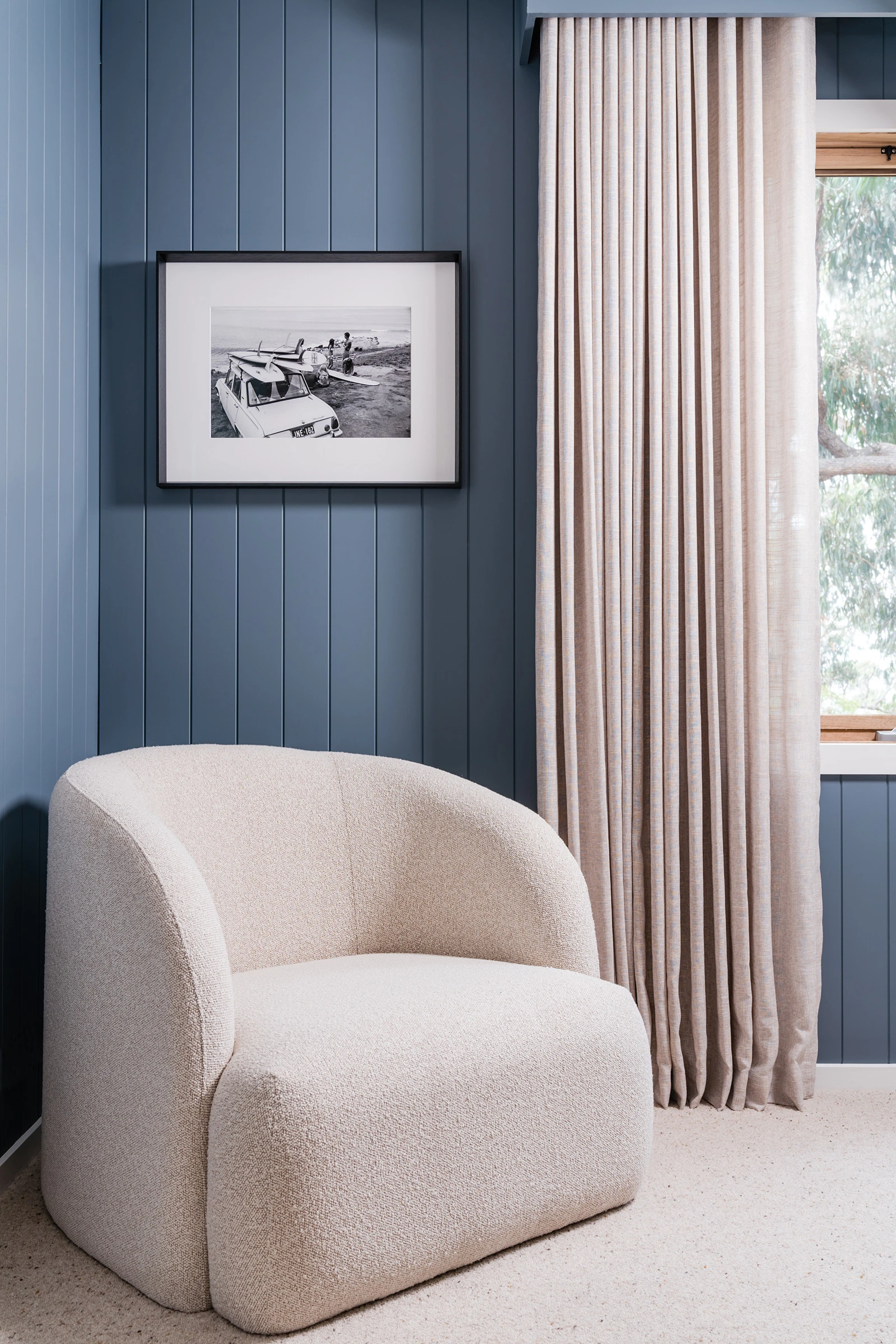 White padded arm chair in guest bedoom with blue walls