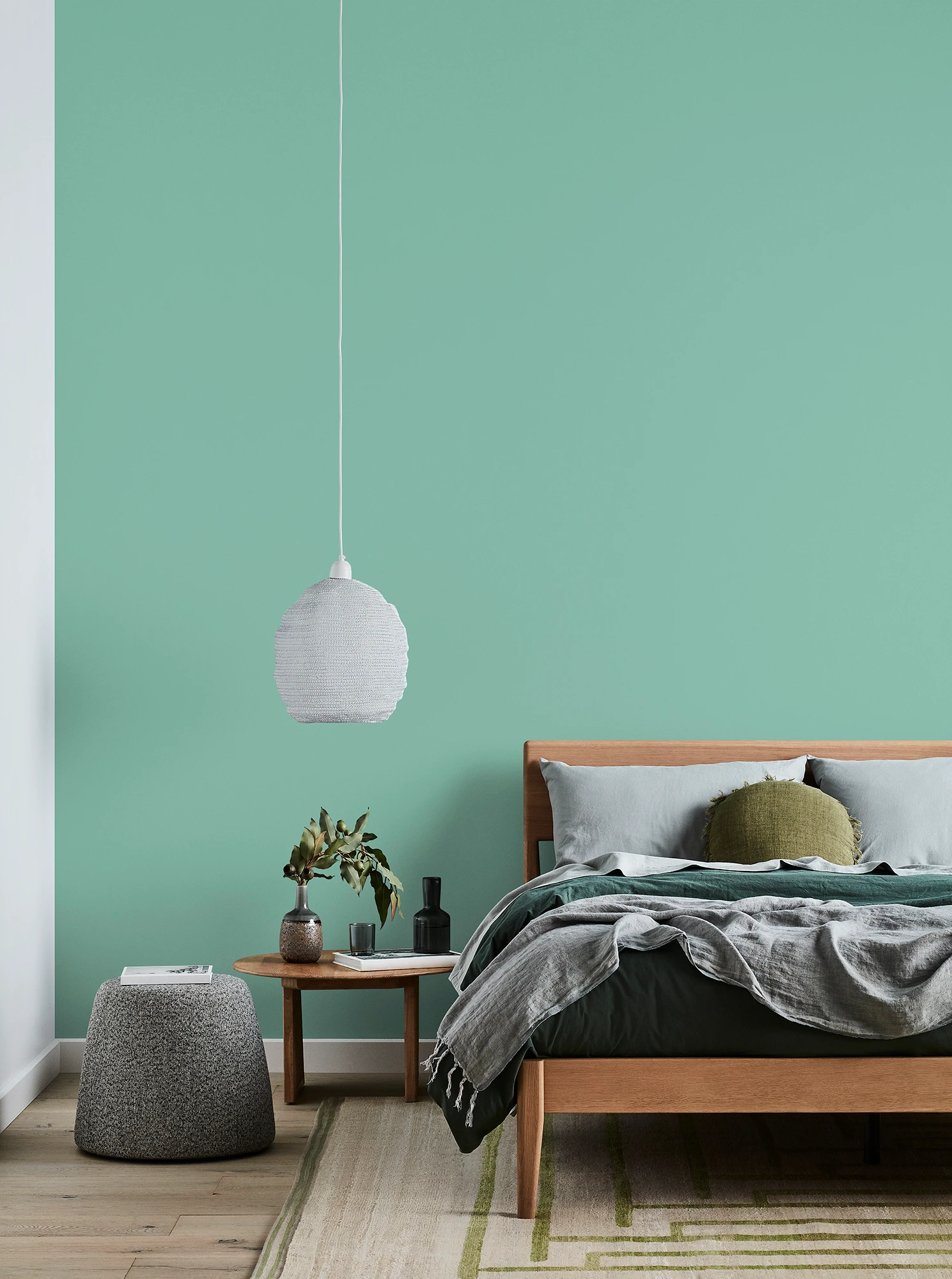 Green bedroom in Dulux Diorite paint. White pendant light.