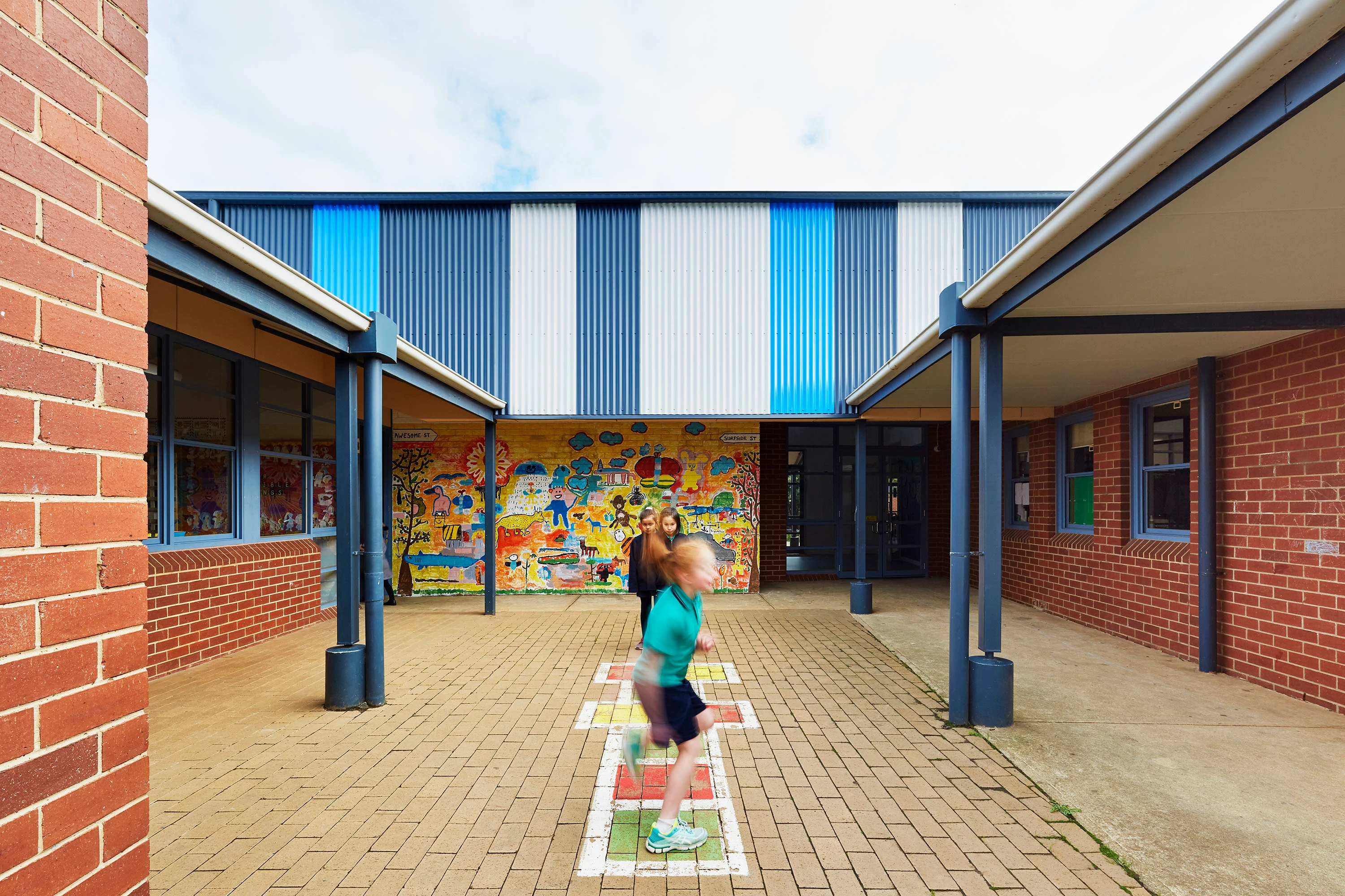 Children playing hopscotch outside school buildings