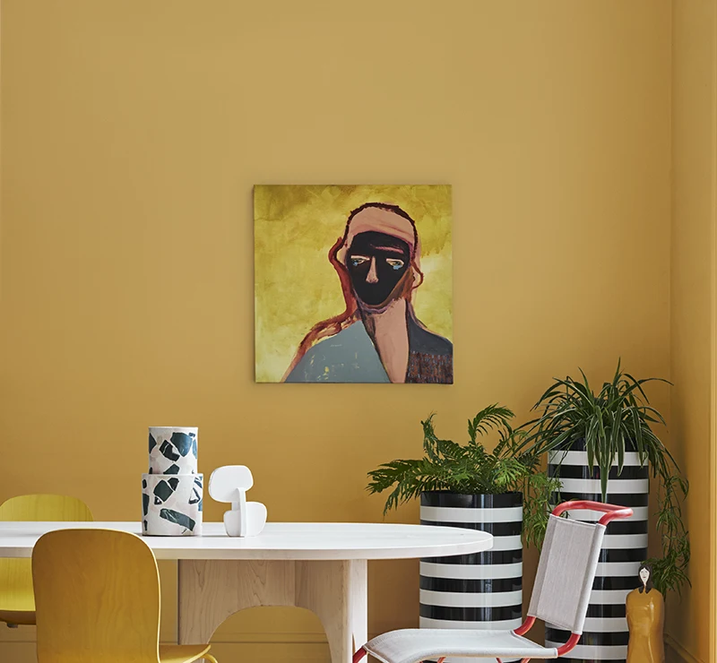 Portrait artwork with yellow background on mustard yellow painted wall