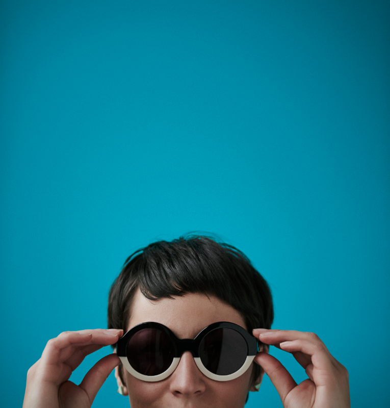 Woman wearing sunglasses with blue backdrop in Dulux Summer Air.