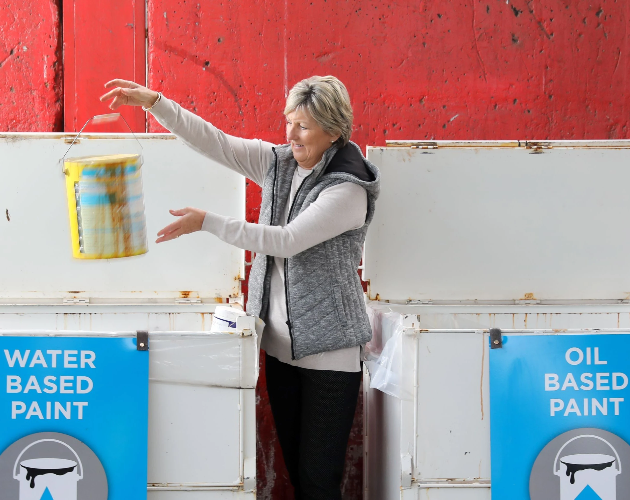 Woman placing used paint tin in recycling