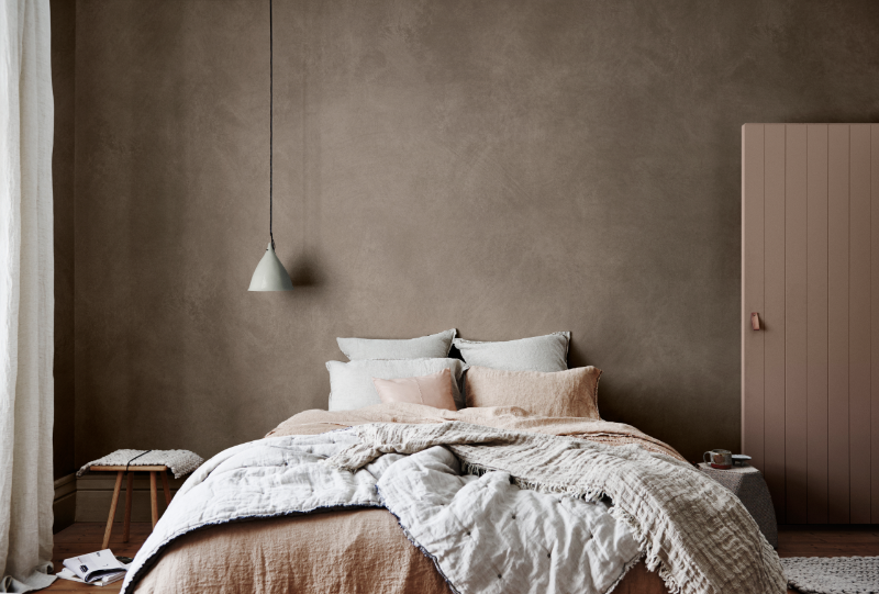 view of neutral bed in front of brown feature wall 