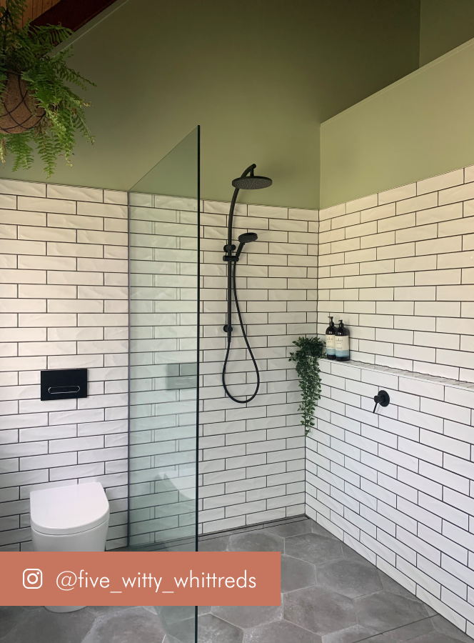 Green bathroom with white subway tiles and black taps and showerhead