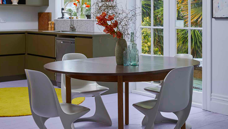 Post modern kitchen, plastic curved chairs with timber dining table in open plan kitchen area.