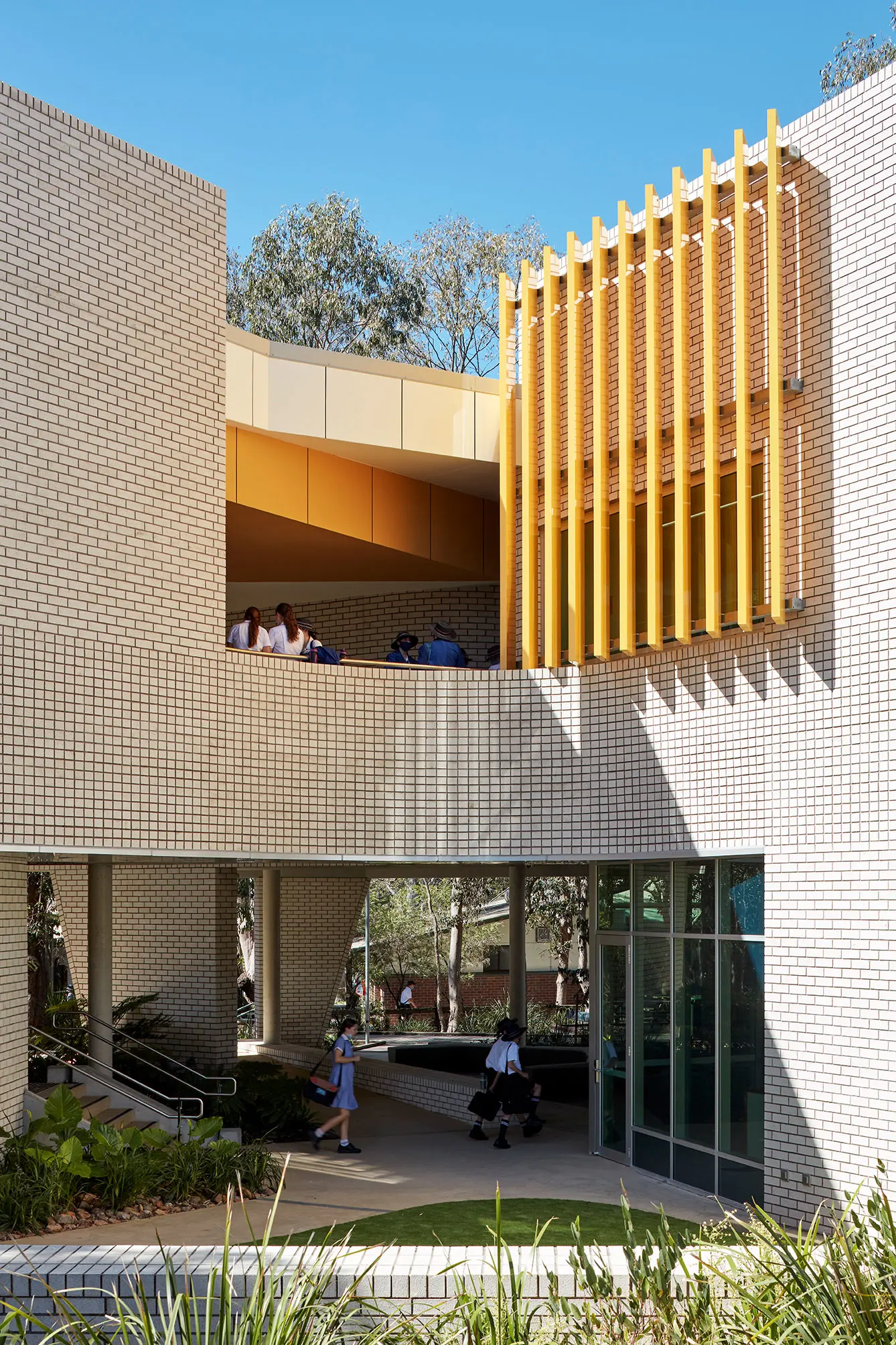 White brick exterior of school with yellow louvres