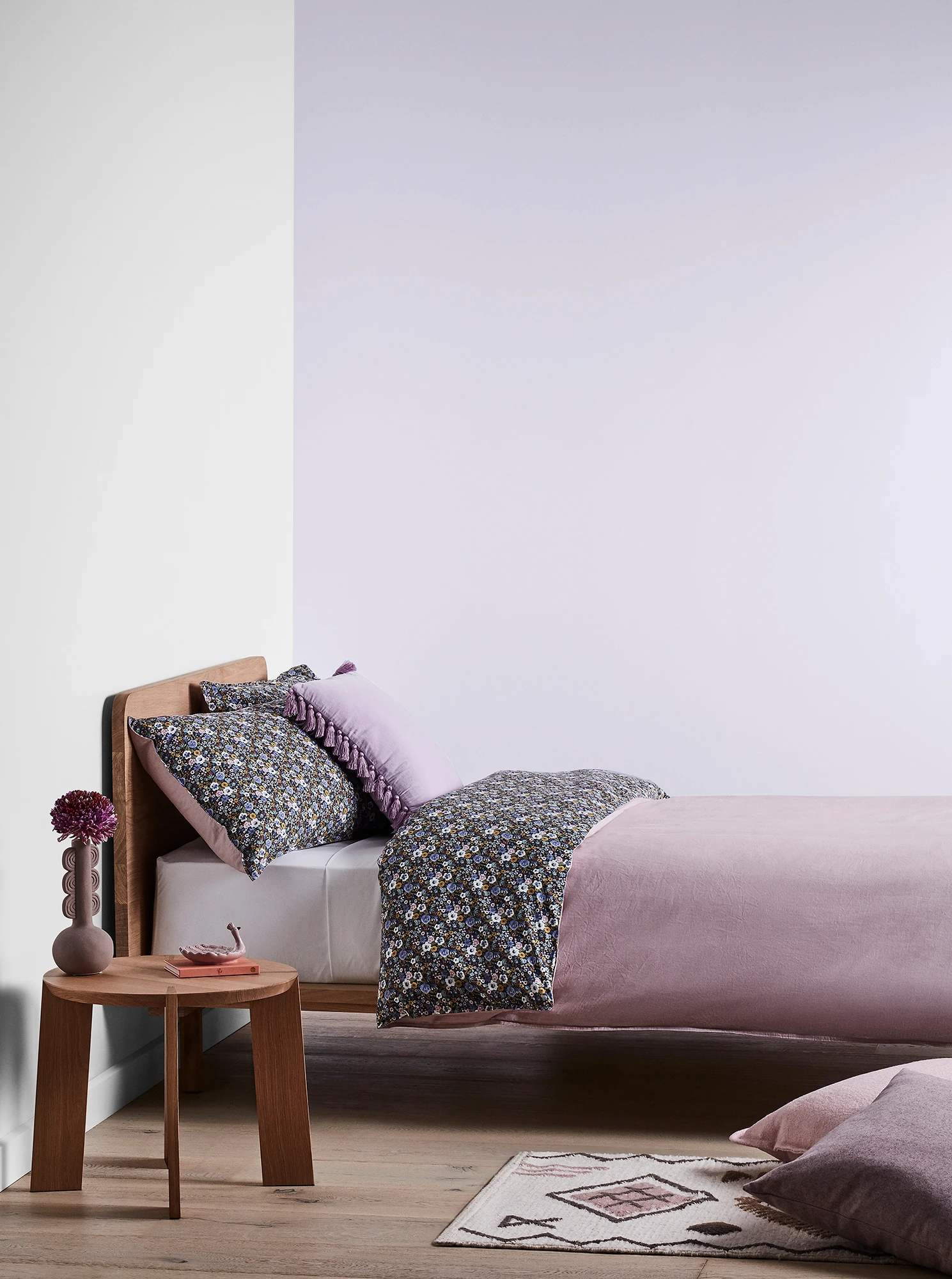 Purple bedroom with timber bed and side table and purple linens.