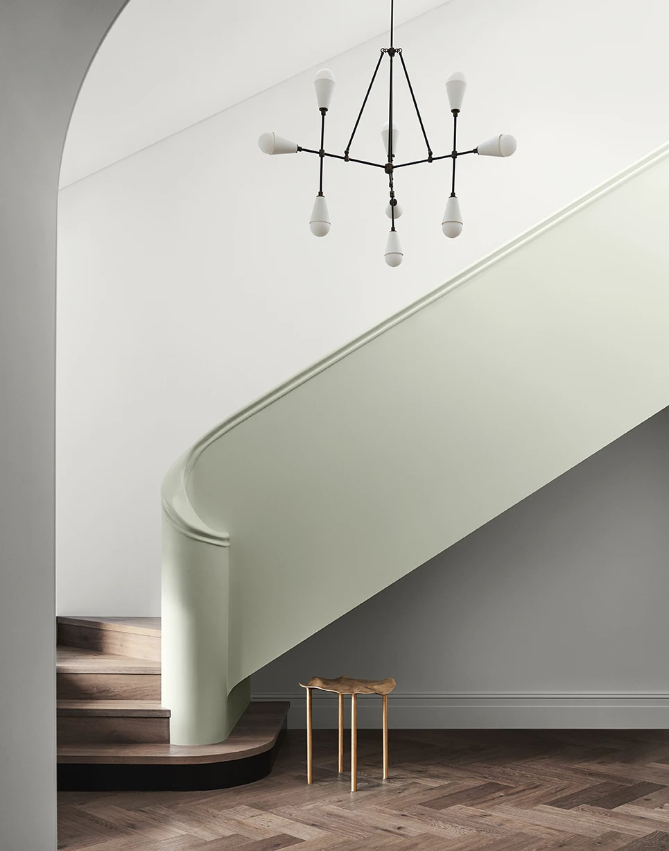 Foyer with light green staircase, parquet timber floors and white walls