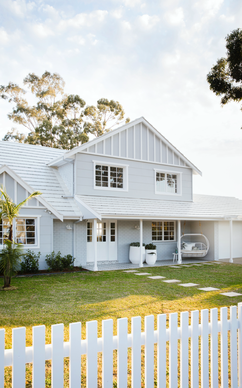 White Hamptons style exterior house with white fence