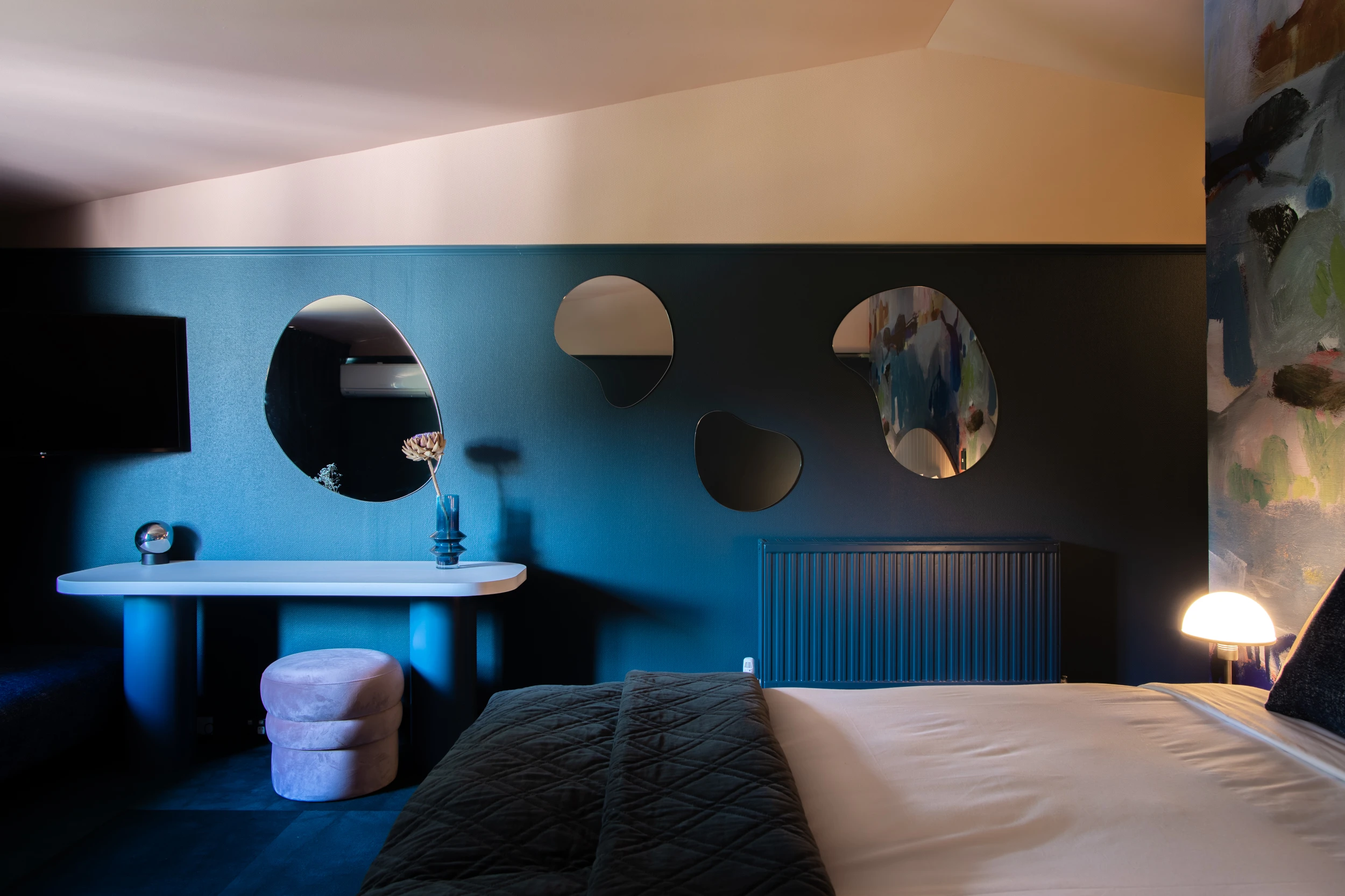 Four irregularly shaped mirrors on a blue hotel room wall