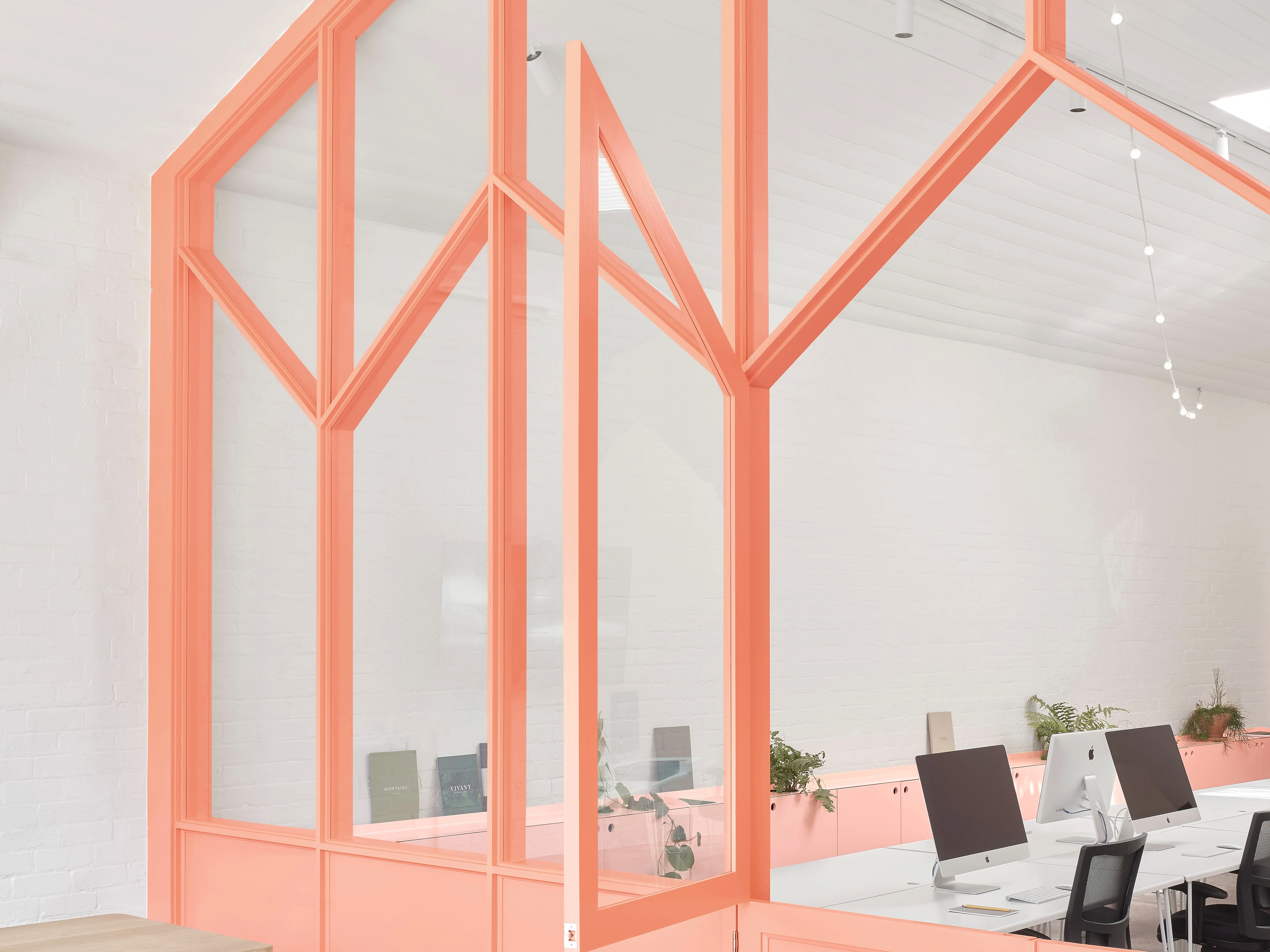 open plan office with artistic framework divider painted in light orange pink