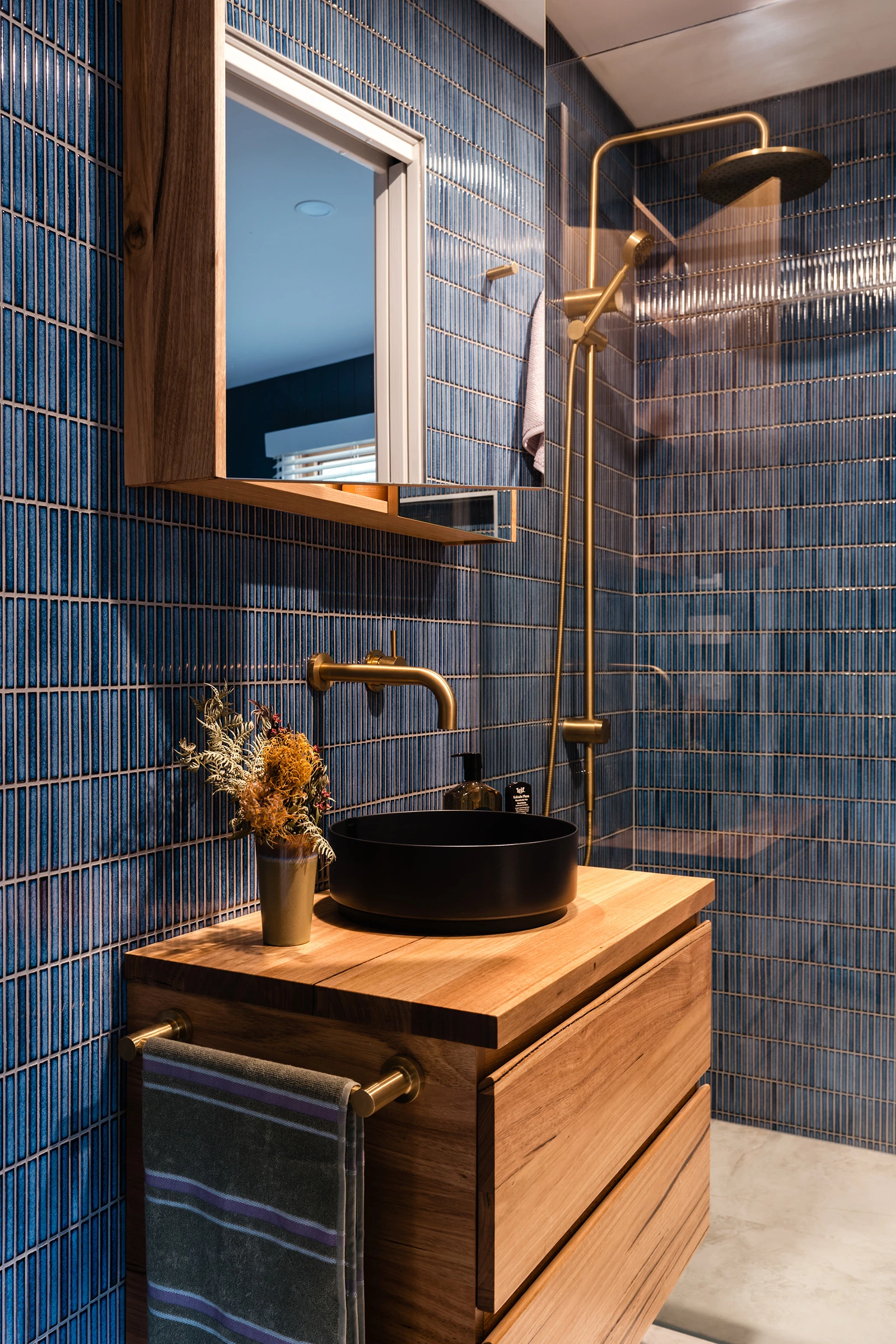 Blue tiled bathroom with timber vanity and black basin