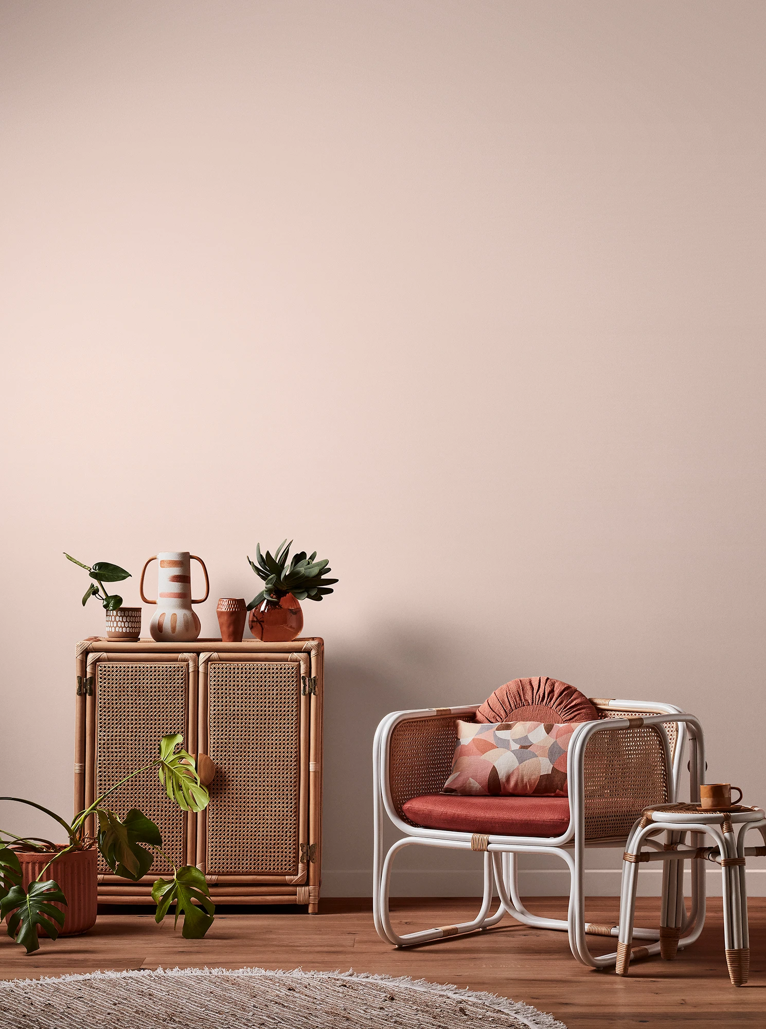 Light pink living room with natural rattan cabinet and white rattan table and chair with pink cushions