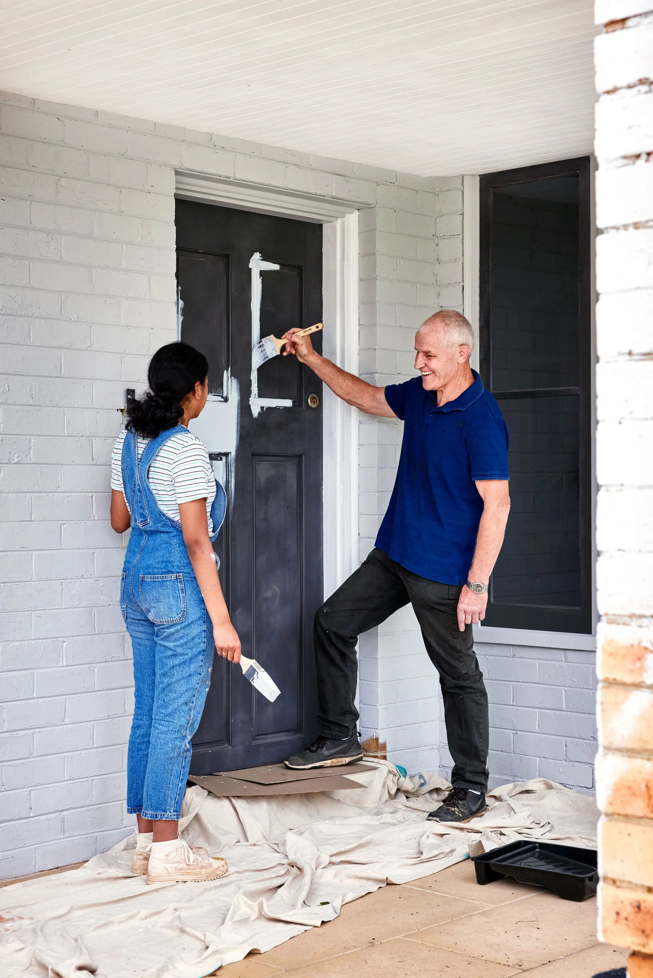 Man and woman painting front door.