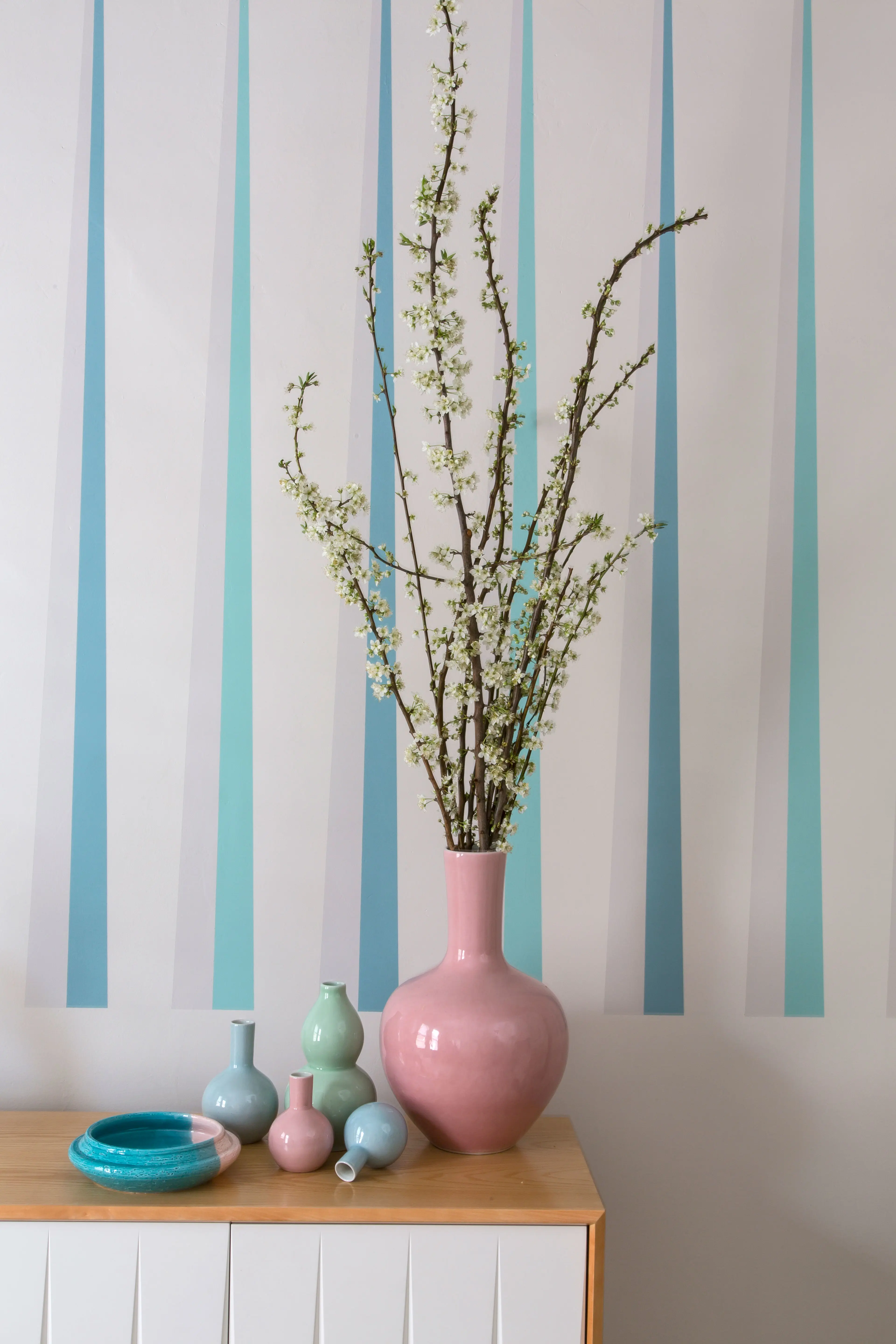 White wall with blue an grey stripes. Pink vase on console. Colour Forecast 2013 - Rise palette 