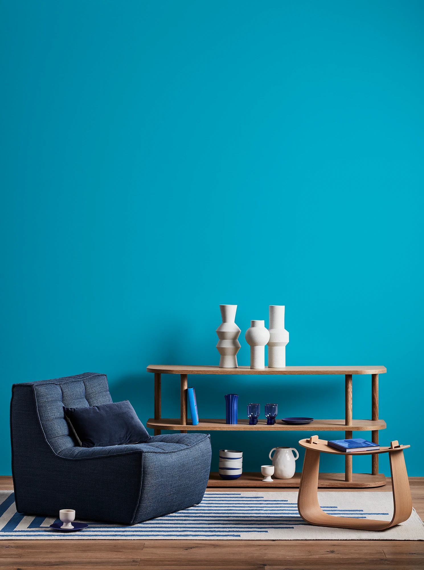 Blue living room with blue armchair, wooden coffee table and shelves with blue and white decor.