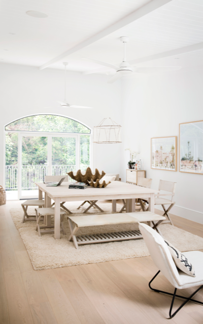 The Hinterland Dream project's white dining room with arched window and cream furniture.