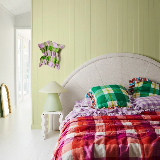 Interior bedroom featuring Queen bed with wooden panelling feature wall painted in Dulux Celery Green. 