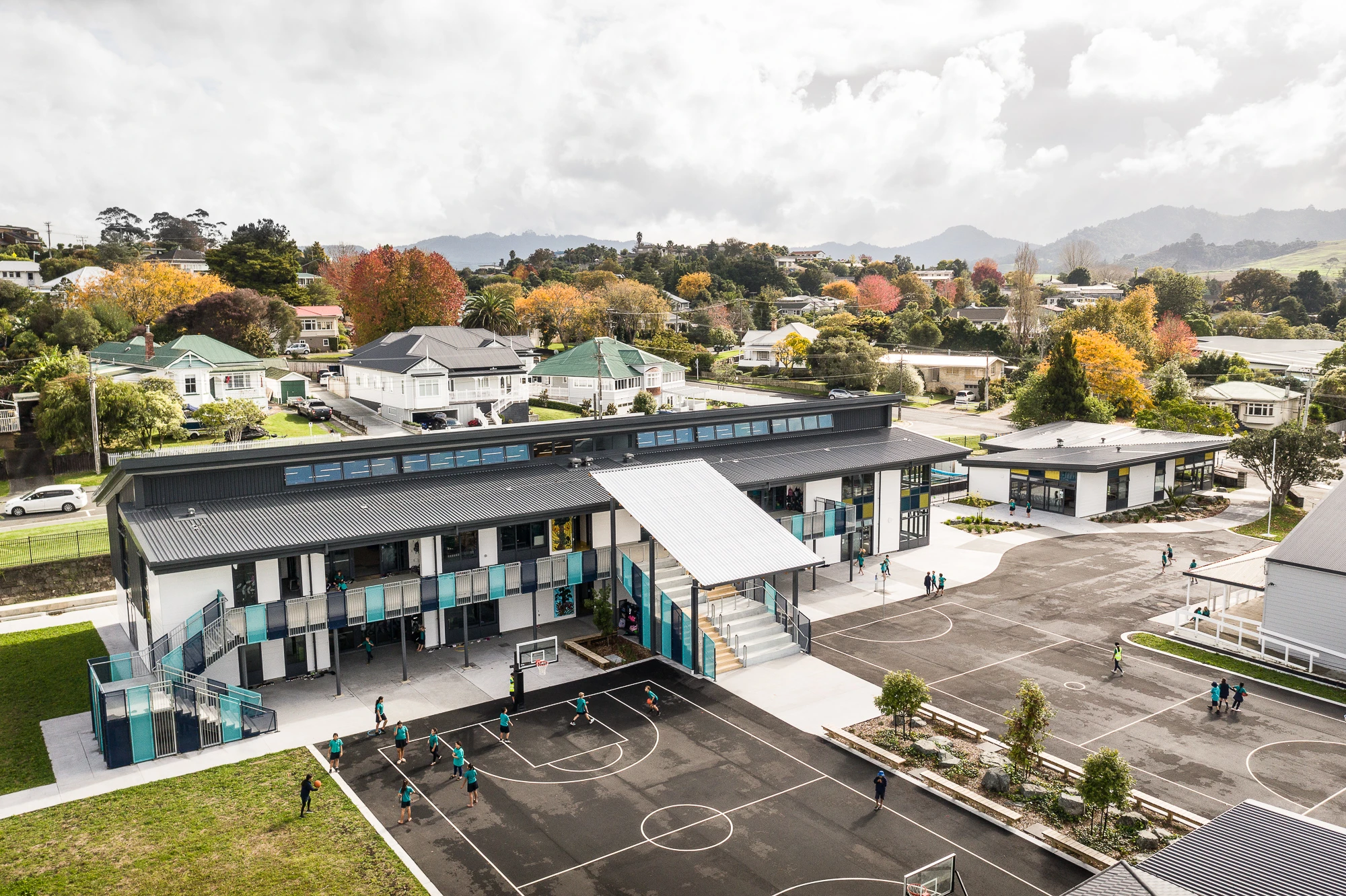 Elevated view of grey, blue and white double-storey school with multipurpose court.