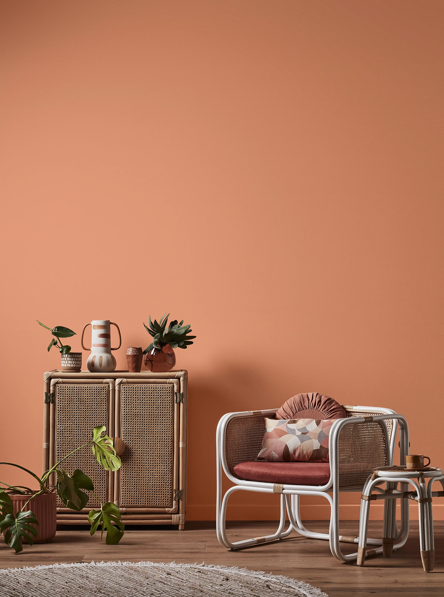 Orange themed seating area with small wicker cupboard and decorative items throughout.