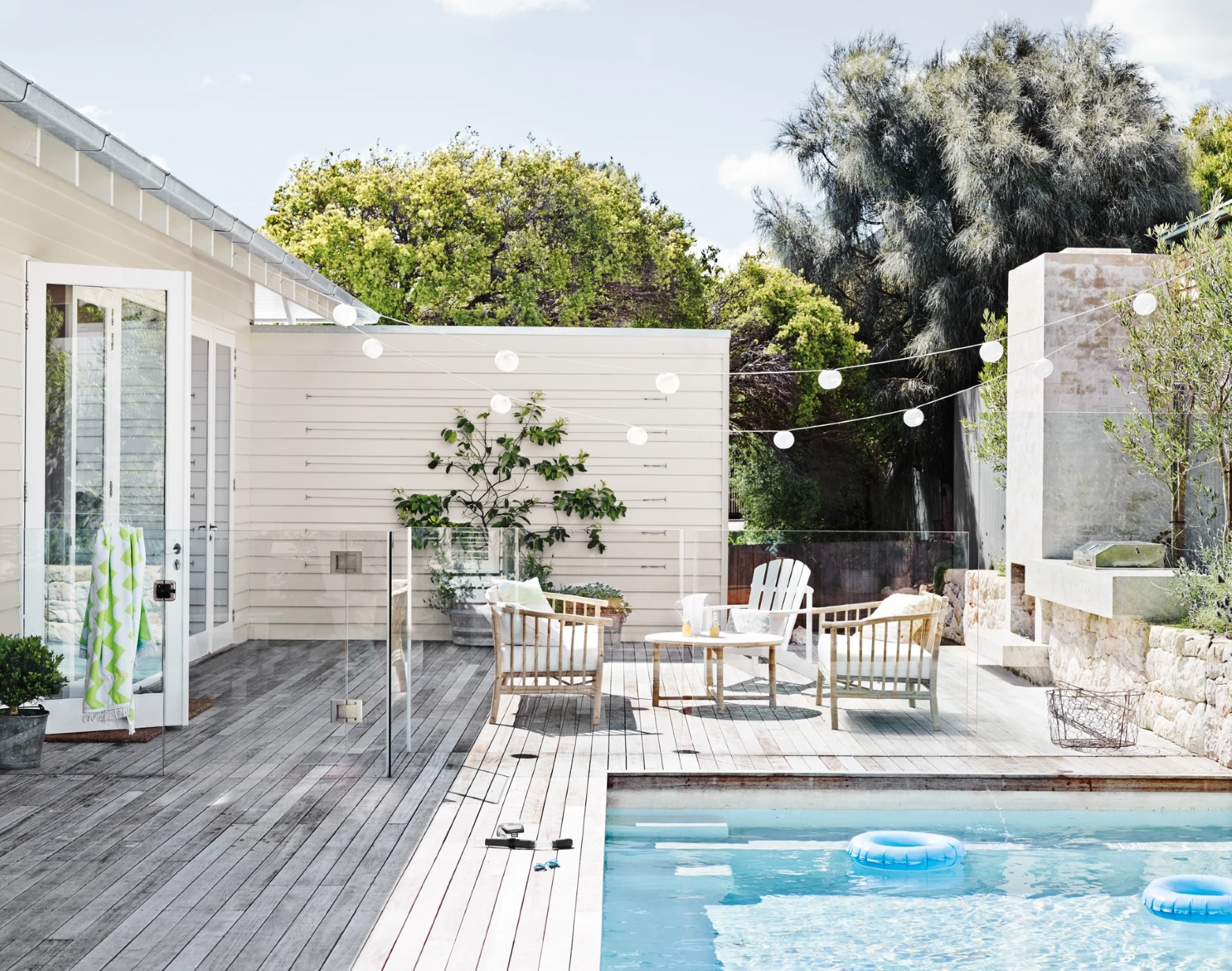 Outdoor pool and deck with white painted walls and seating area