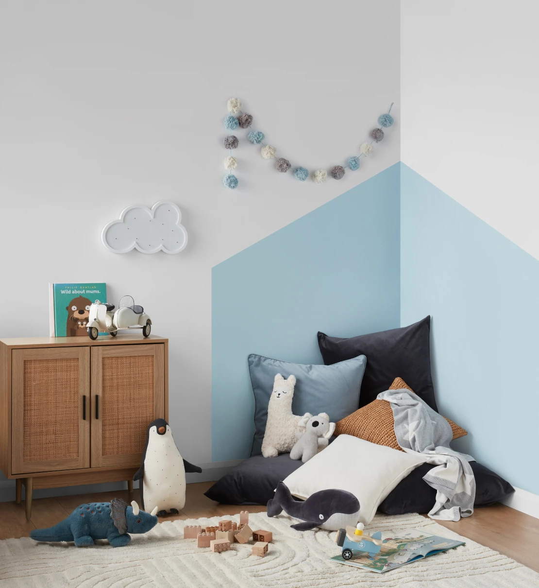 Kids room with Vanilla Ice Half coloured geometric shape in the corner of the wall and Vivid White surrounding wall. Children's toys and soft cushions occupy the space.