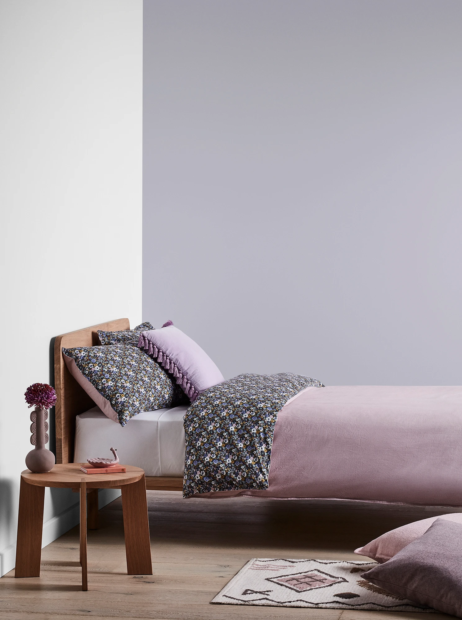 Purple bedroom with timber bed and side table and purple linens.