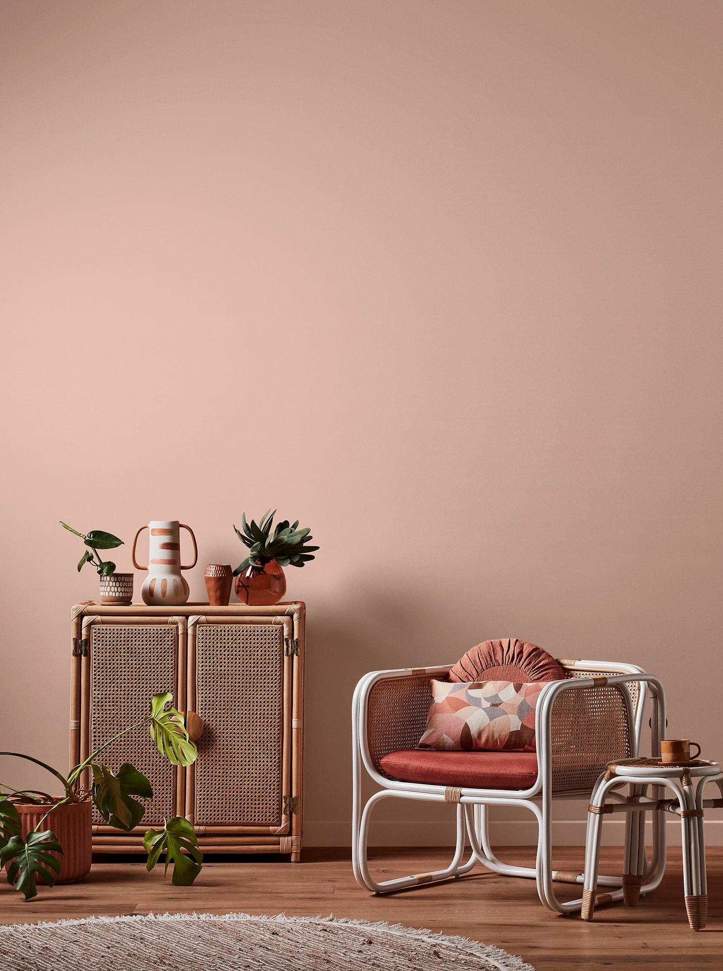 Light orange living room with natural rattan cabinet and white rattan table and chair with pink cushions