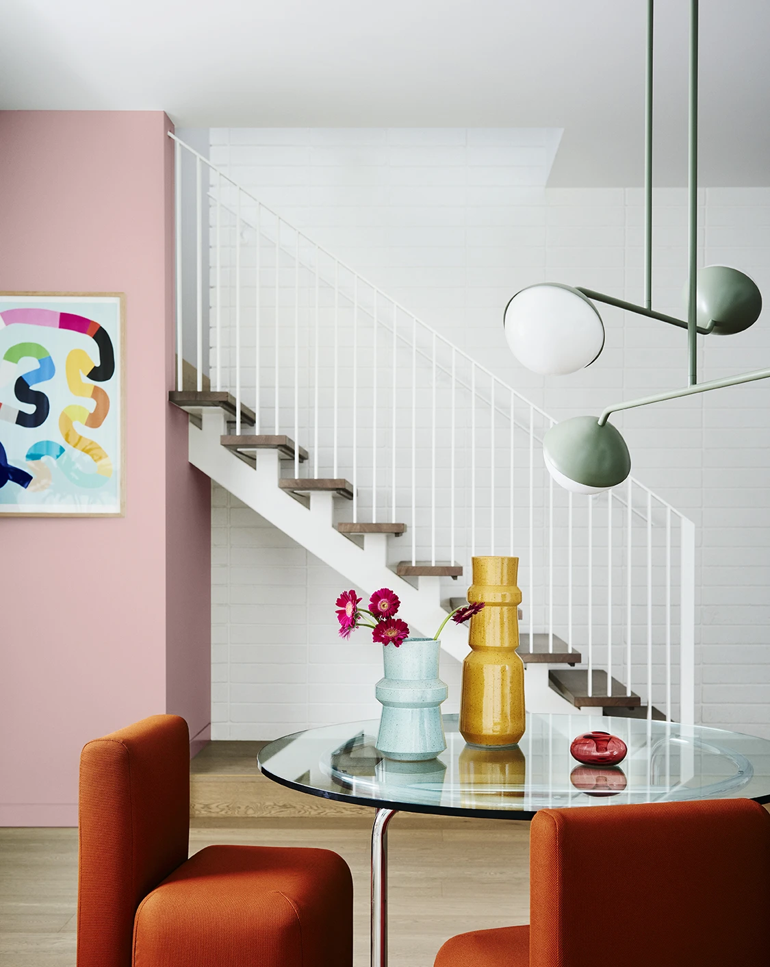 Dining room with view of pink feature wall and white stairs