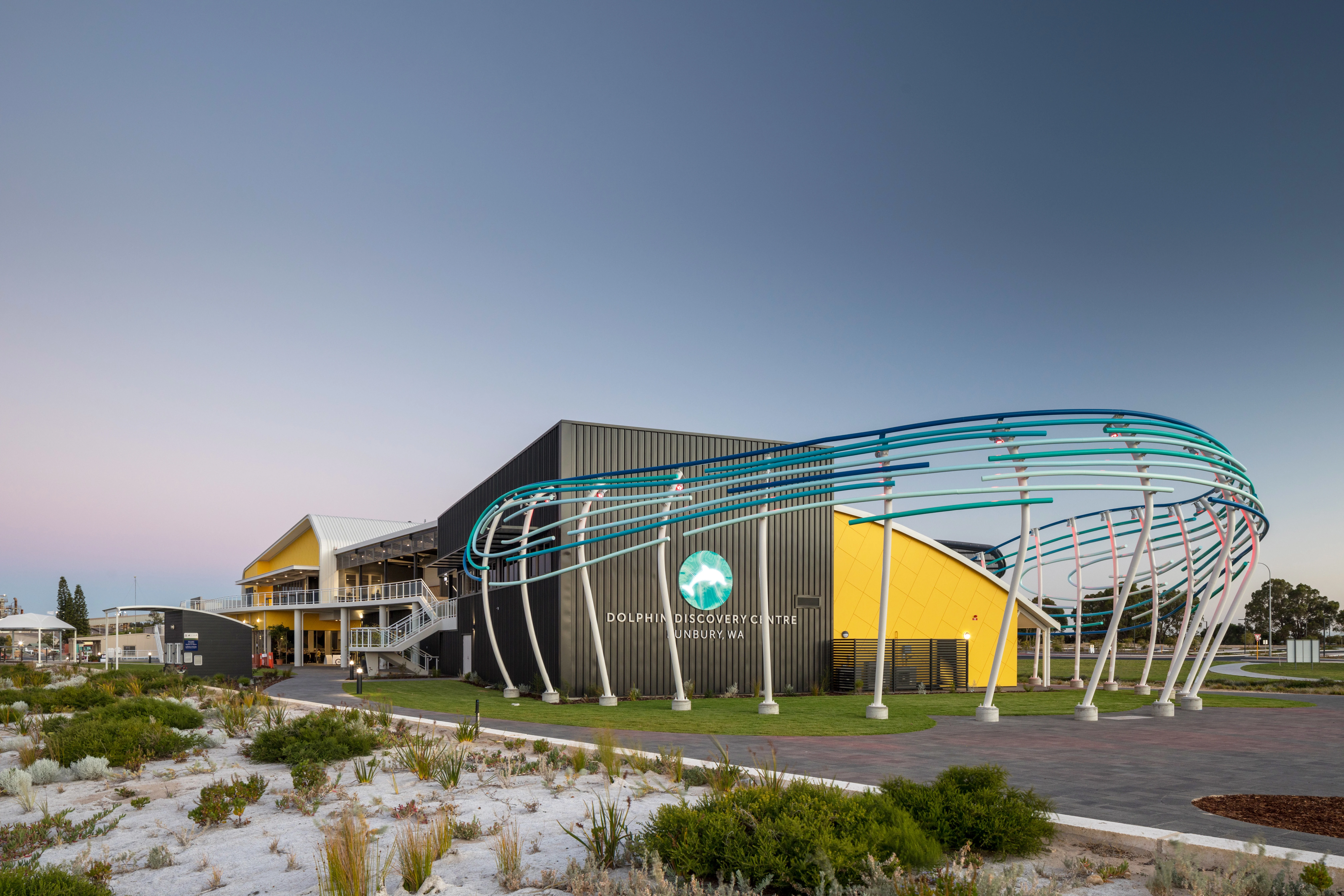 Black and yellow curved building with artistic curved blue bars at the front of the building.