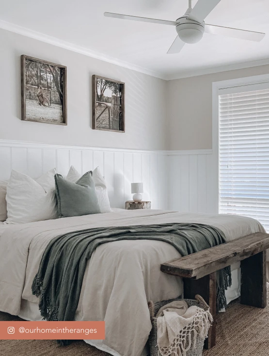 Bedroom featuring neutral linen bed spread and white wooden board panelling half way up the wall.