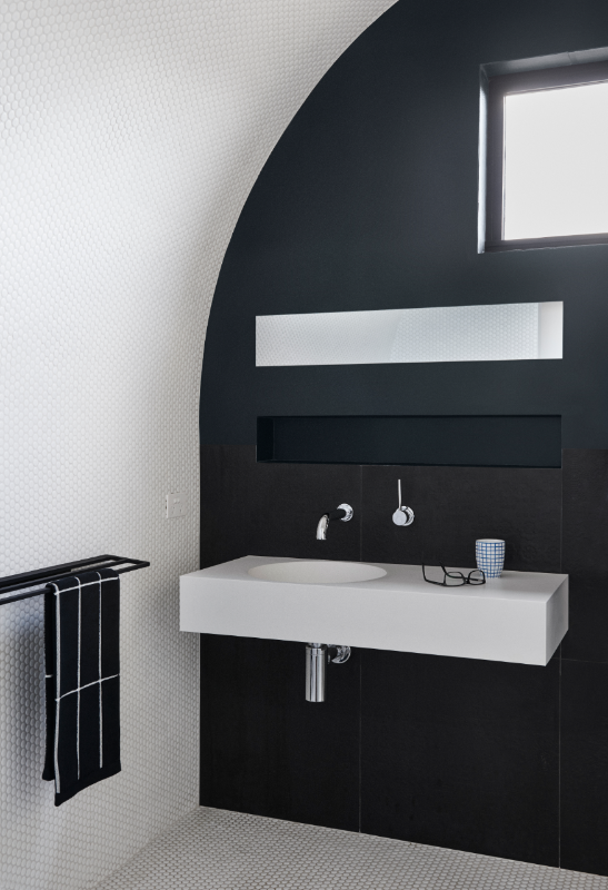 A white bathroom vanity attached to a black bathroom wall. 