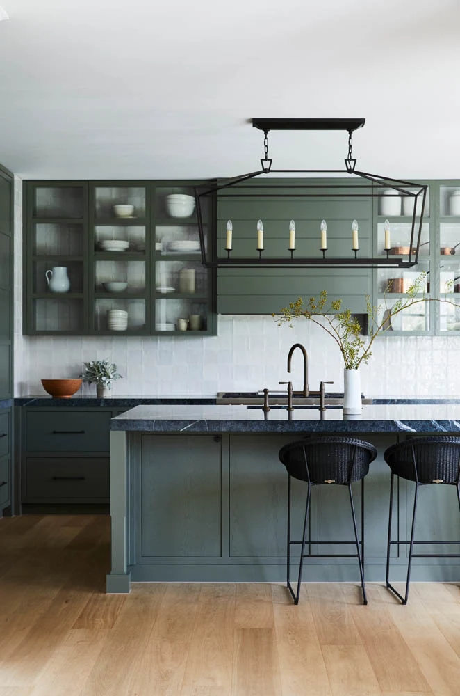 Kitchen with white ceiling and splashback, island bench and dark green cabinets