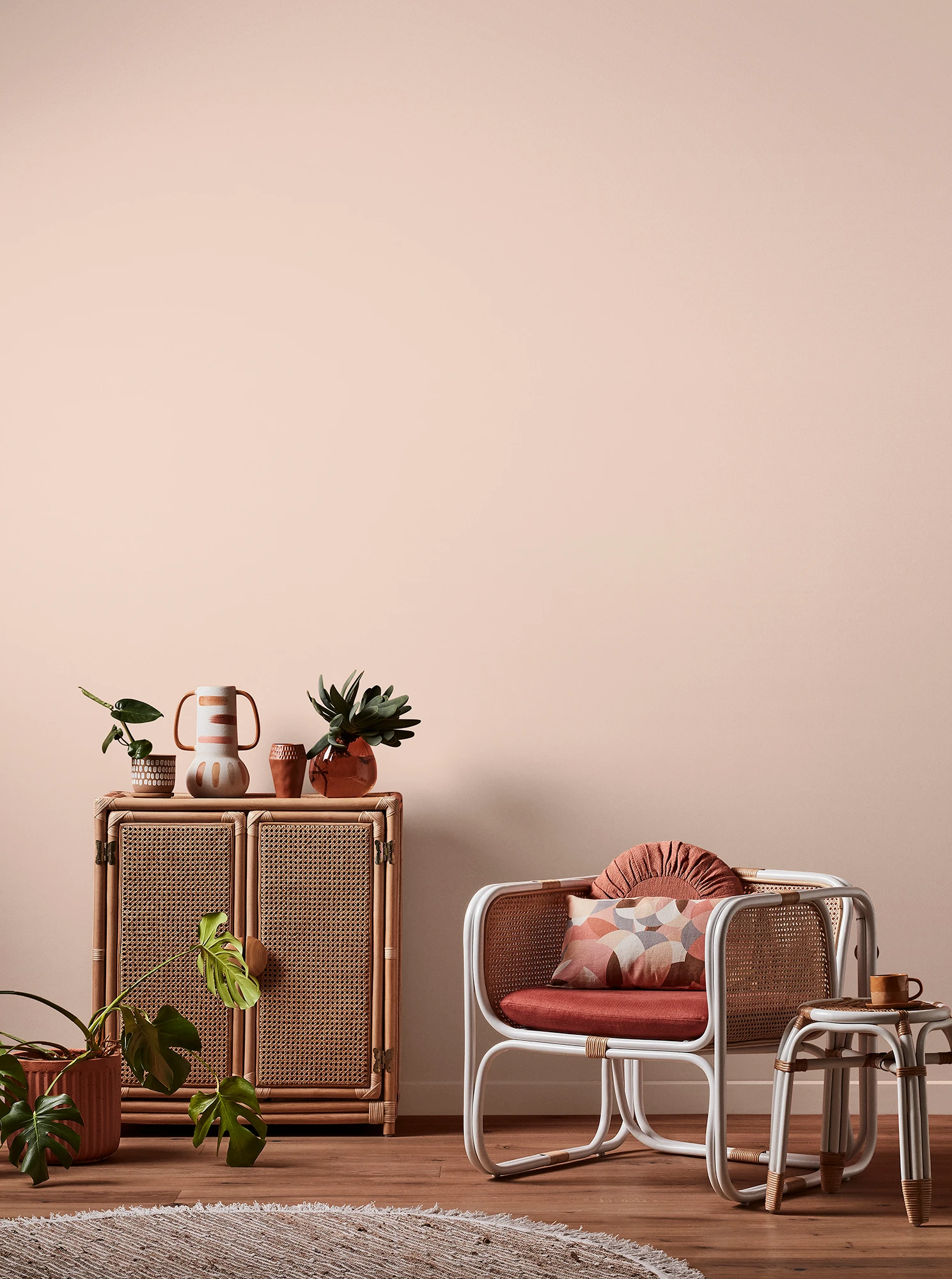 Light pink living room with natural rattan cabinet and white rattan table and chair with pink cushions