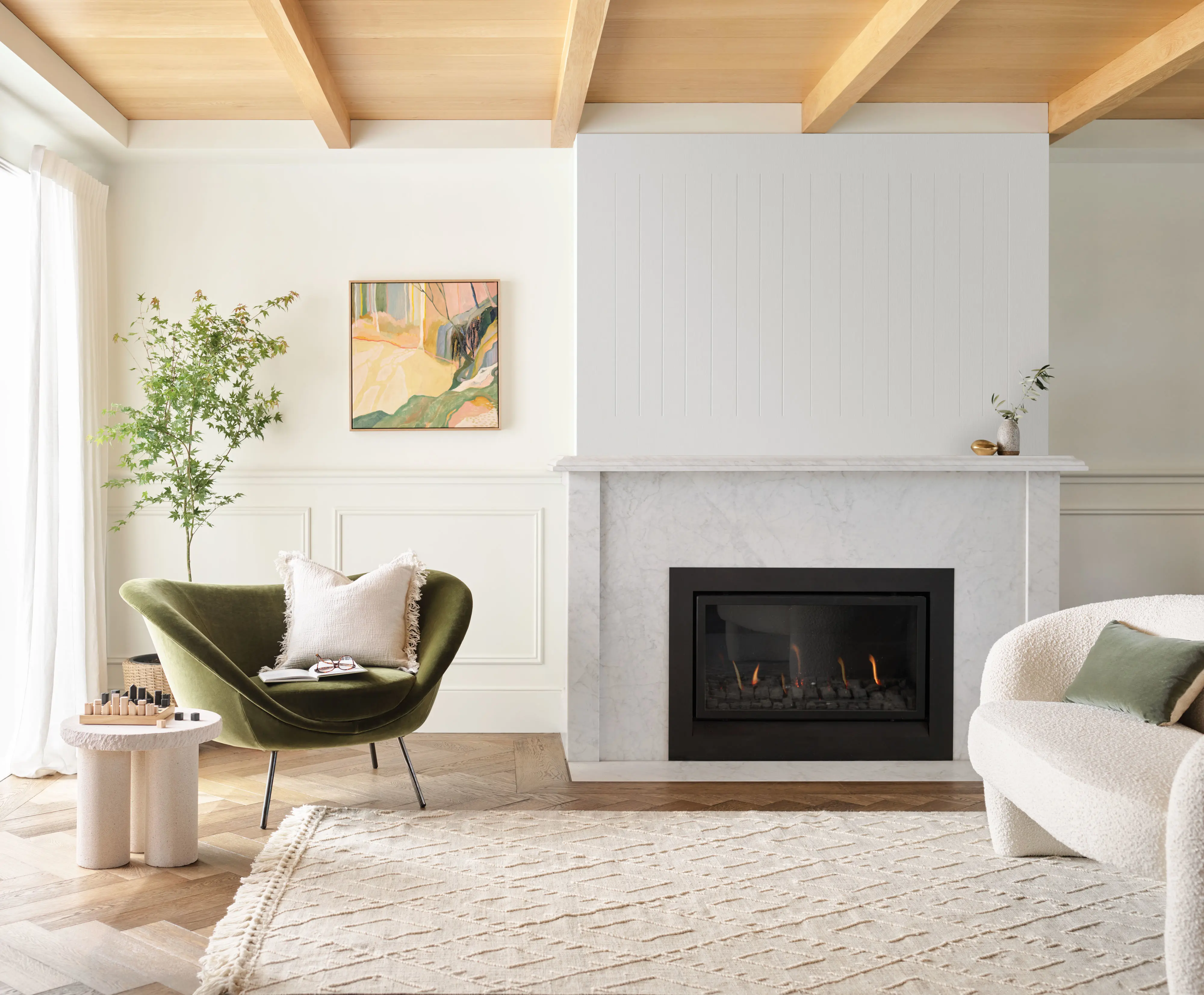 White living room with a a timber ceiling, green arm chair and fireplace
