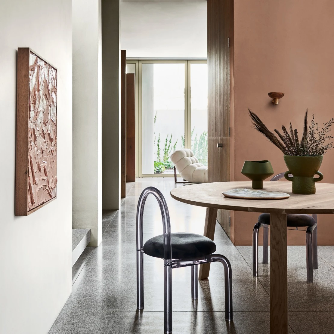 View of kitchen to hallway showing small dining table and hanging light, and lightly painted walls in background.