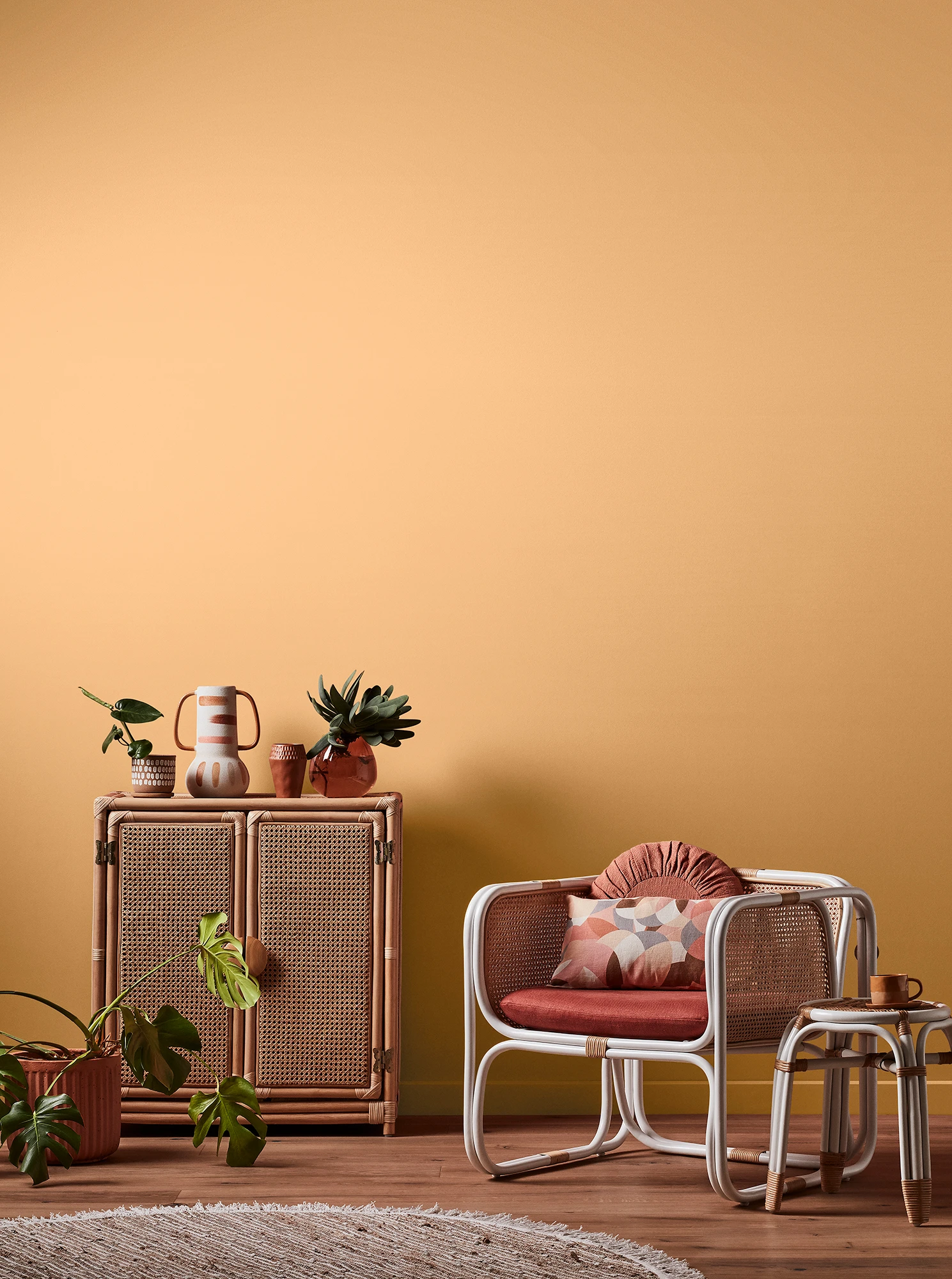 Light orange living room with natural rattan cabinet and white rattan table and chair with pink cushions