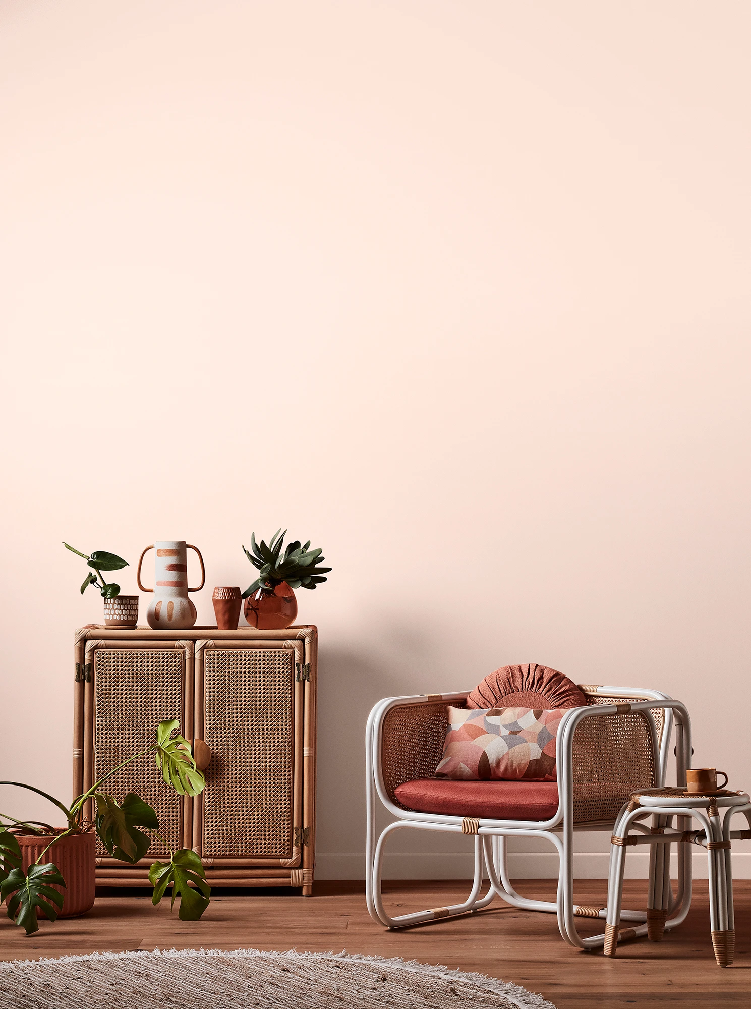 Light pink living room with natural rattan cabinet and white rattan table and chair with pink cushions