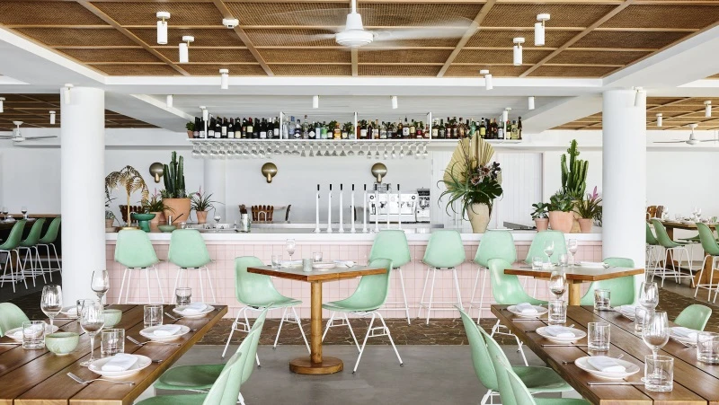 interior dining setting, with green chairs and pink bar.