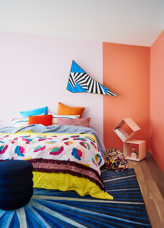 Multi-coloured bed in front of a pink wall