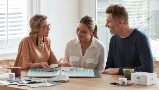 Dulux Colour Consultant pointing to colour chart with two people sitting at a table. 