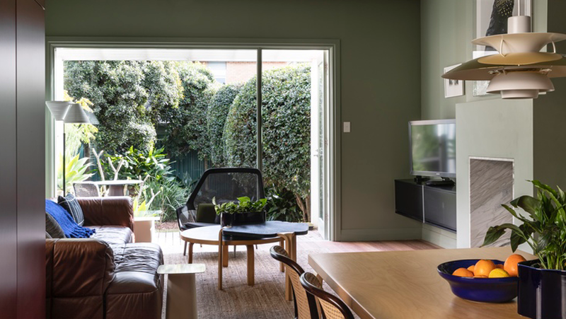 Green living area with couch, fireplace and timber dining and coffee tables