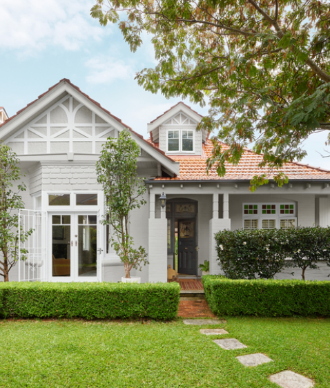 Neutral weatherboard house, white double doors with stained glass inset, white trim.