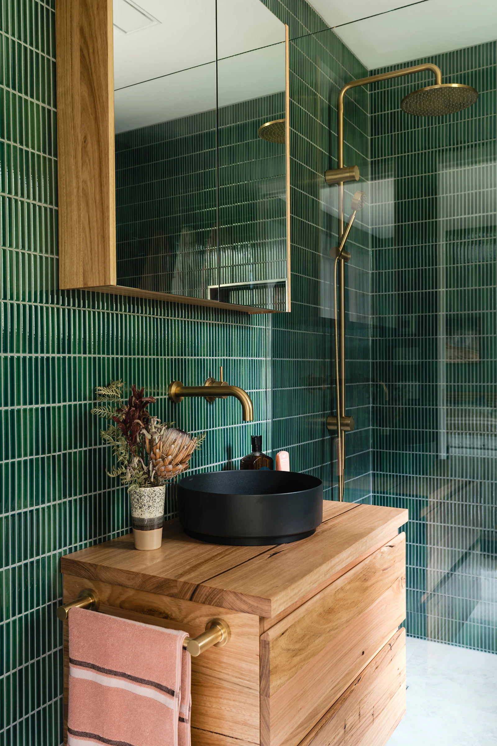 Green tiled bathroom with timber vanity and black basin