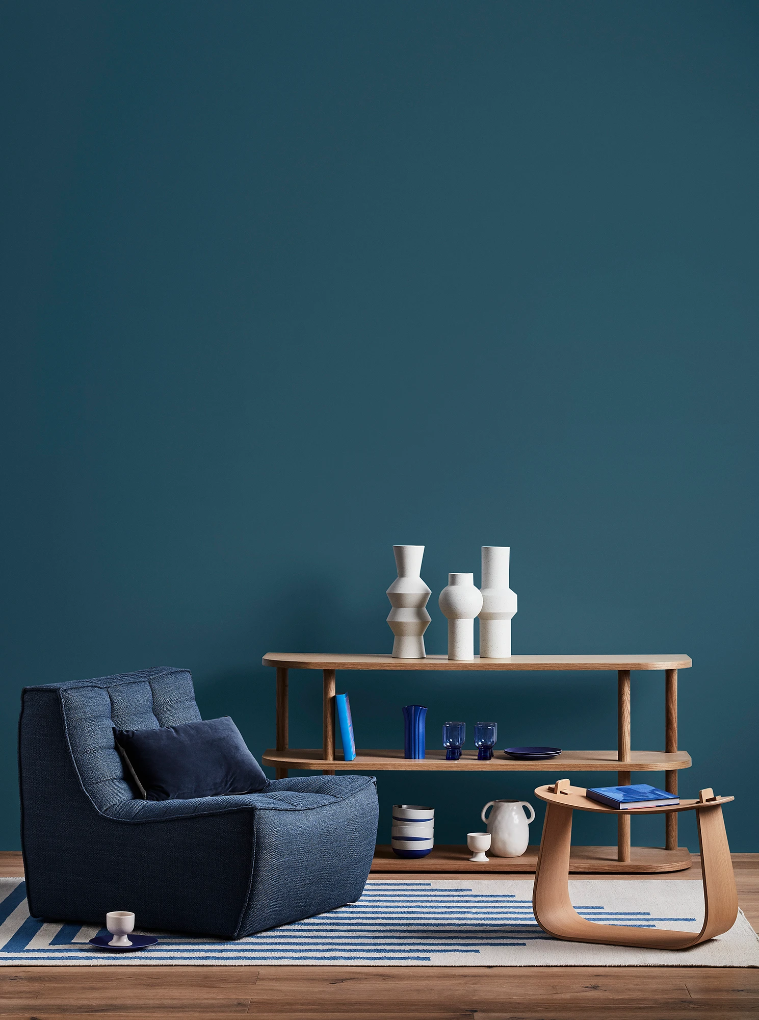 Blue living room with blue armchair, wooden coffee table and shelves with blue and white decor.