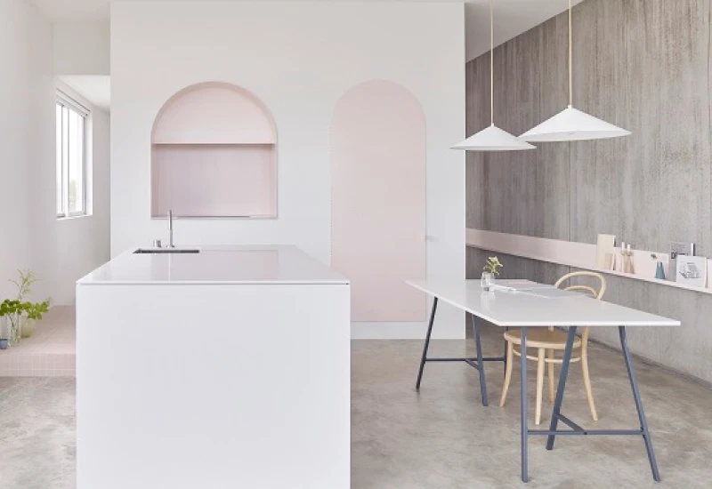 Pink and white kitchen with concrete wall and polished concrete floor