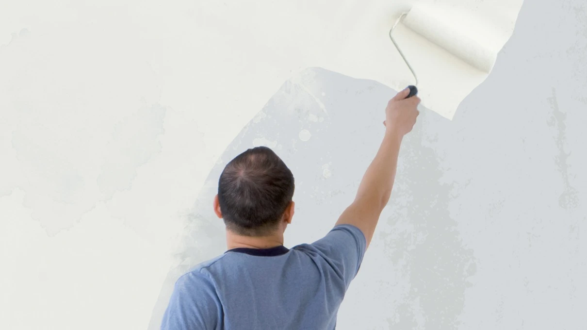 man applying paint to wall with roller